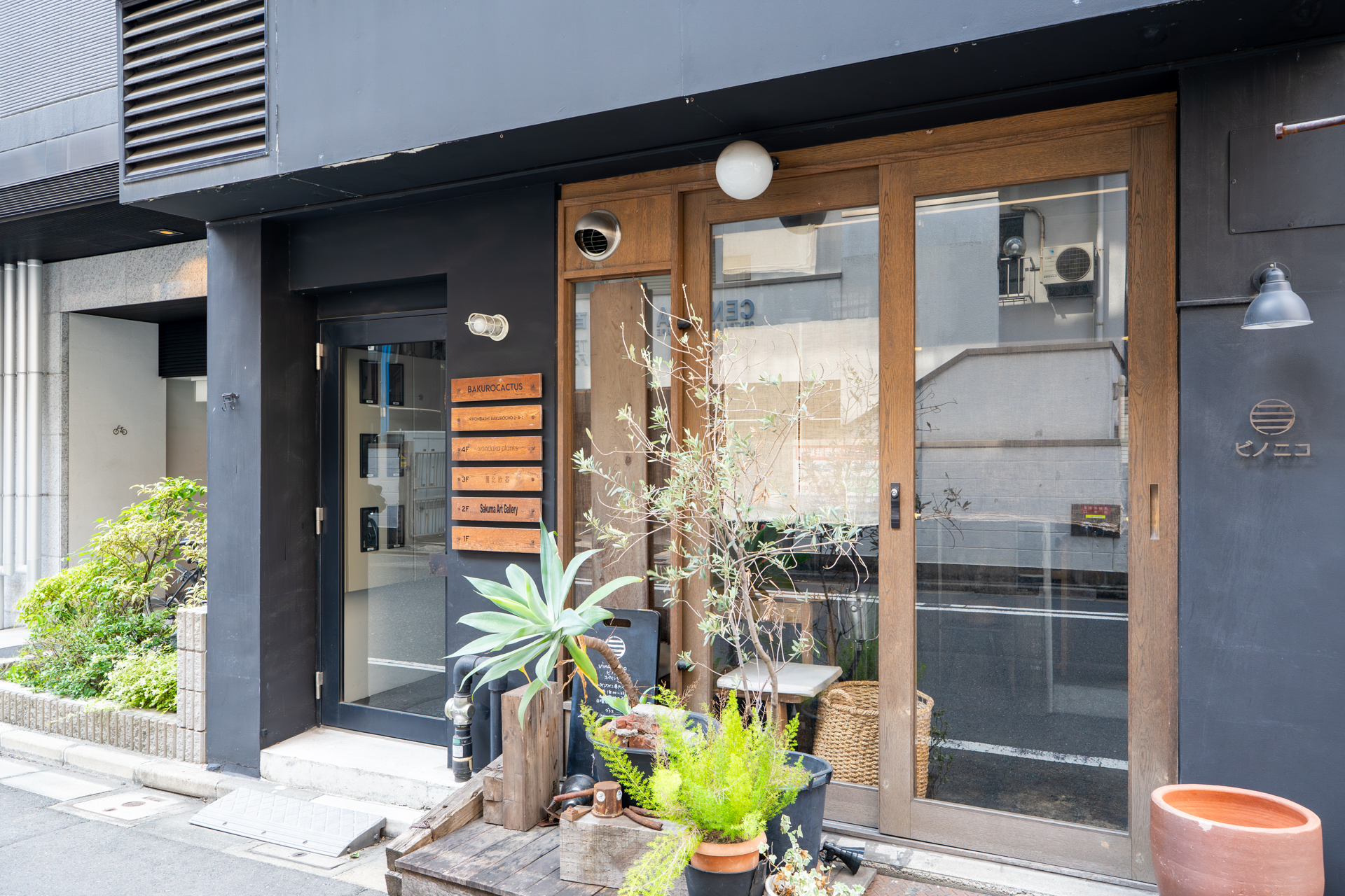 左側の黒いドアの先、階段を上った4階部分。店舗サインはドア右側の木の館銘板にどうぞ