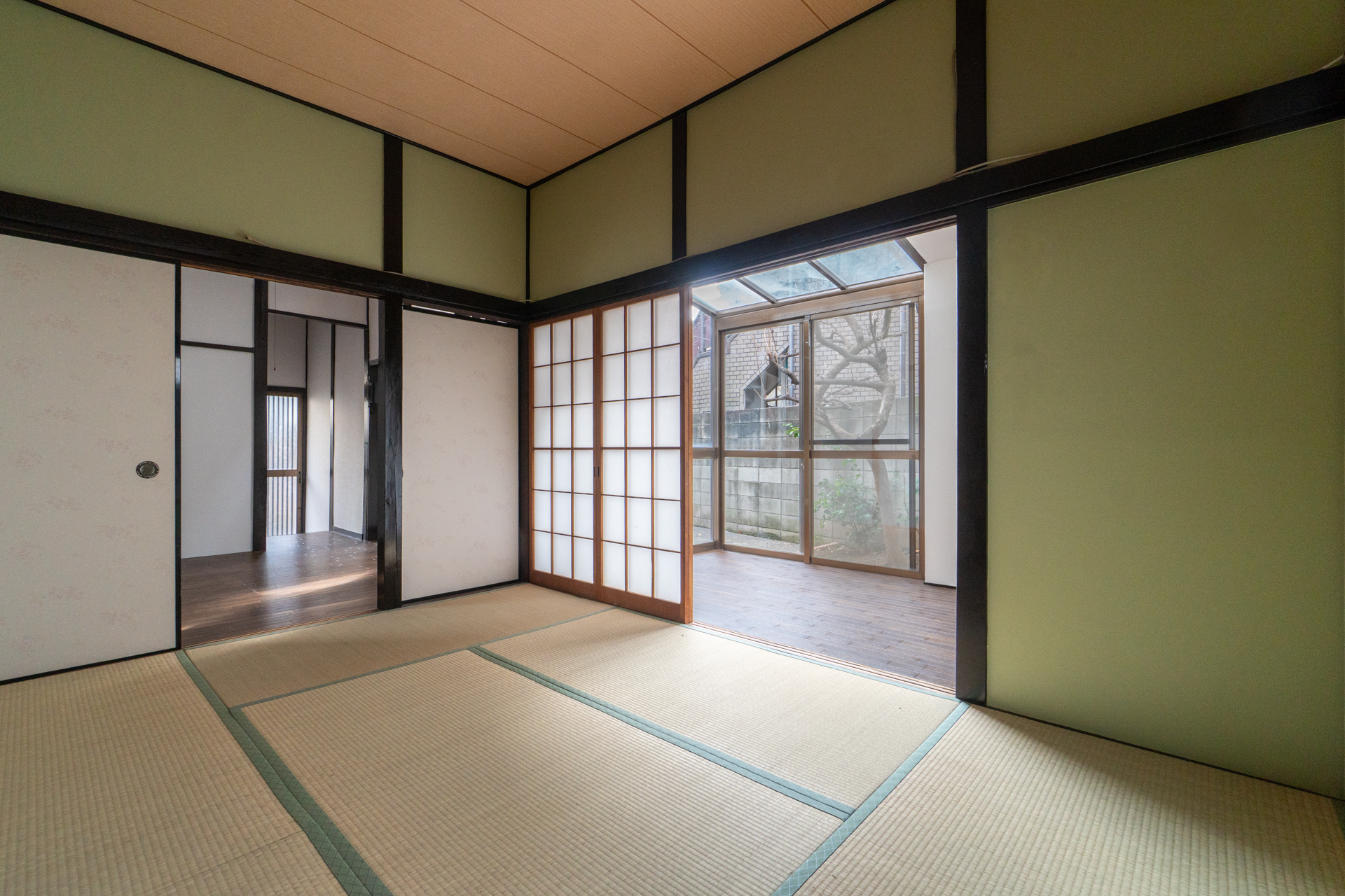 一階和室からサンルームごしに庭を眺める