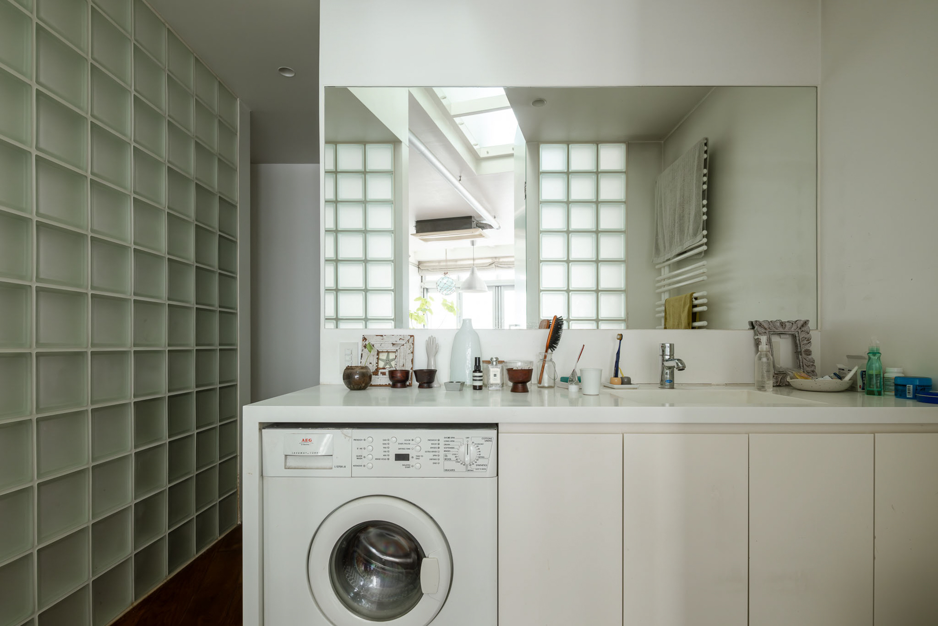 ガラスブロック、ビルトイン洗濯乾燥機、タオルウォーマーの組み合わせがどこか日本離れした雰囲気のある水回り